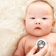 Baby on a fur rug with a stethoscope.
