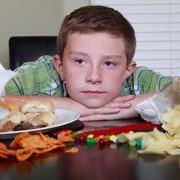 Boy sitting at table piled with junk food.