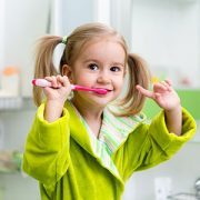 Little blond girl brushing teeth.