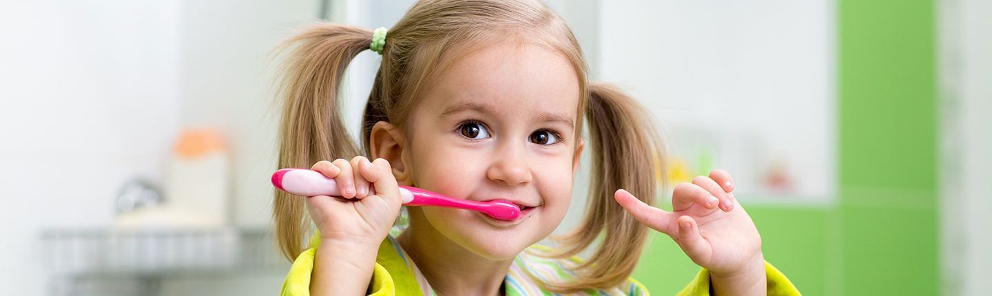 Little blond girl brushing teeth.