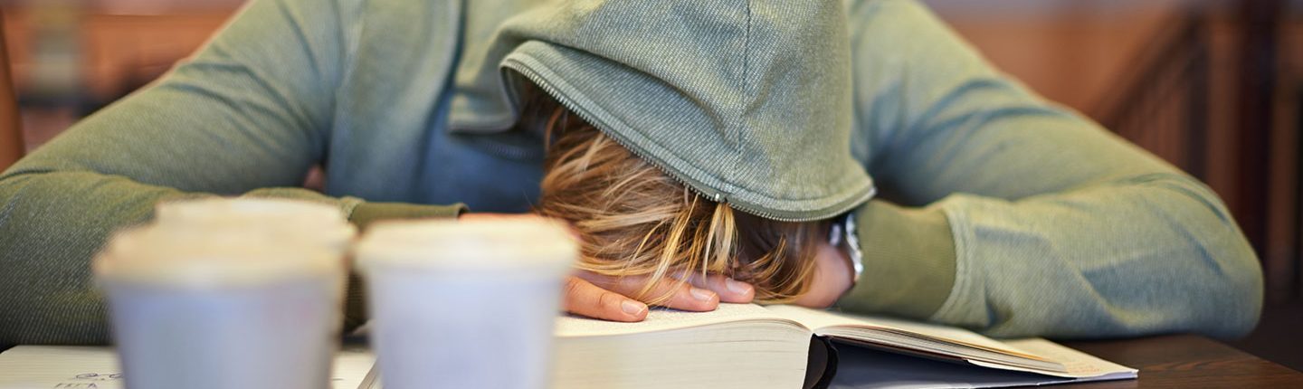Teen siting at desk asleep on a book.