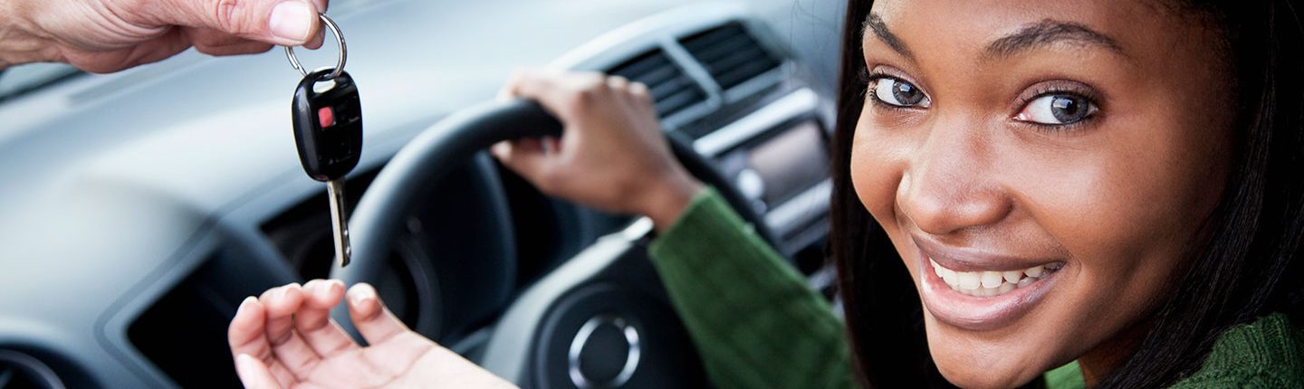 Teen girl sitting in car being handed the keys.