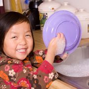 Little girl washing dishes.