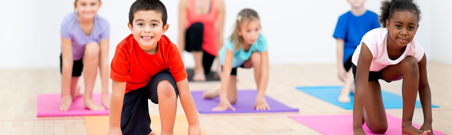 Kids doing yoga in a gym