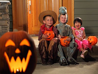 Kids in Halloween costumes sitting in front of a house