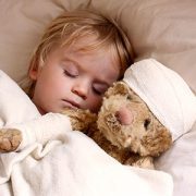 Sick little boy asleep in bed with teddybear