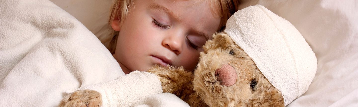 Little boy asleep in bed with teddybear