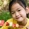 little girl eating fruit kabob
