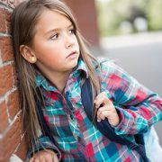 little girl leaning against wall