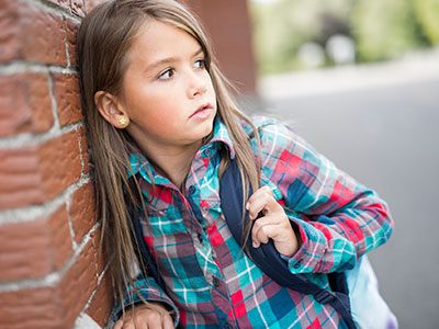 little girl leaning against wall