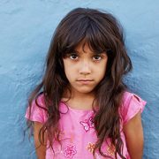 little girl standing against blue wall