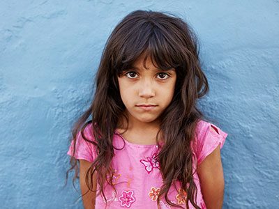 little girl standing against blue wall