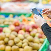 Person in produce aisle with smartphone