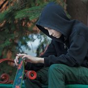 sad teenager looking at skateboard in his hands