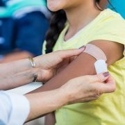 Doctor applies bandage to girl's arm following flu shot