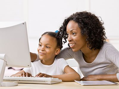 mom and daughter looking at computer monitor