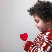 Little kid looking at a heart shaped lollipop