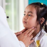 Pediatrician examining little girl's lymph nodes