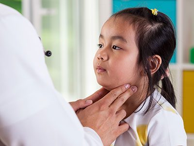 Pediatrician examining little girl's lymph nodes