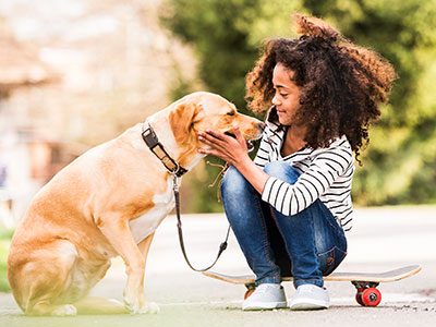 girl sitting on skateboard with her dog