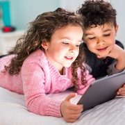 Cute brother and sister enjoying tablet at home