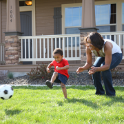 Little boy kicking soccer ball with mom