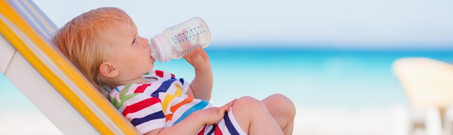 baby drinking from bottle on the beach