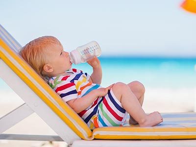 baby drinking from bottle on the beach