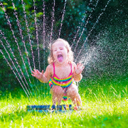 little girl playing in sprinkler