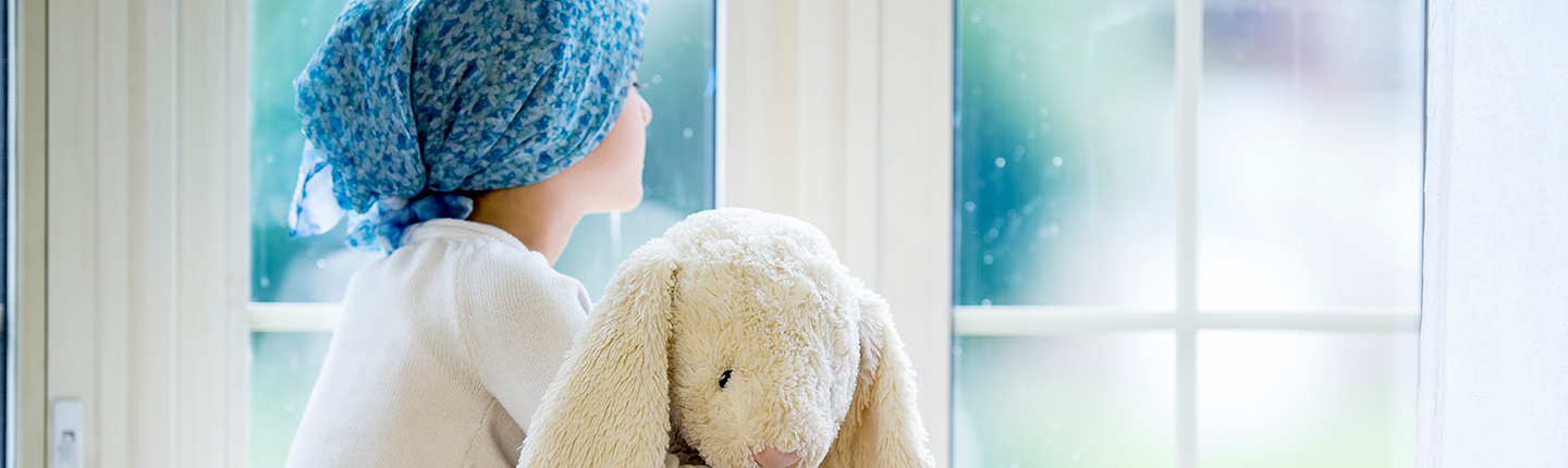 girl with stuffed rabbit looking out window
