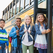 school children standing outside bus