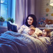 mom reading book to son and daughter in bed