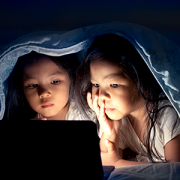 two girls in bed looking at a tablet