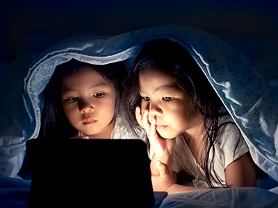 two girls in bed looking at a tablet