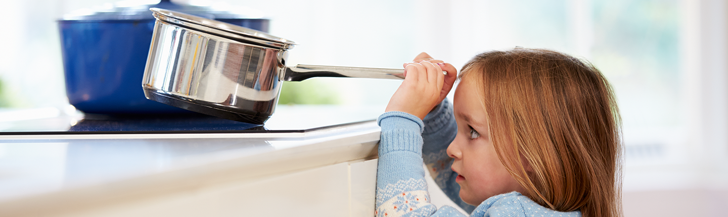 little girl grabbing pot on stove
