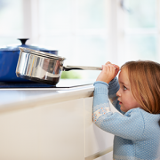 little girl grabbing pot on stove
