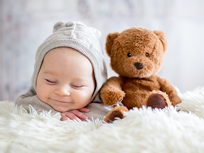 baby boy sleeping in bed with teddy bear