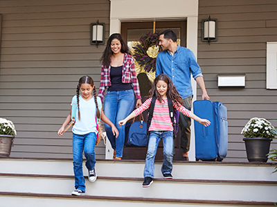 family with luggage leaving house
