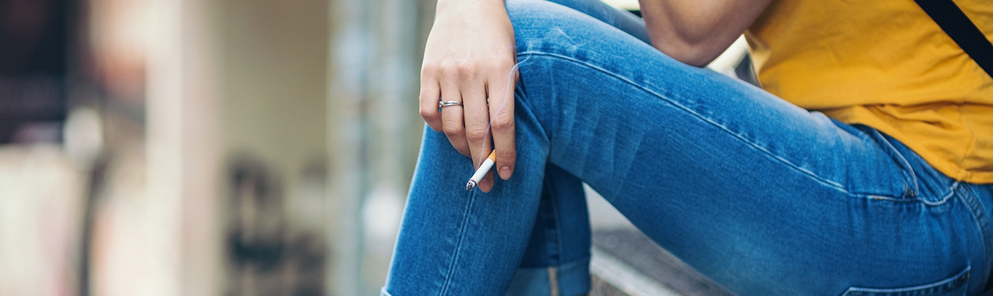 Teenage girl sitting on the staircase outdoors and smoking