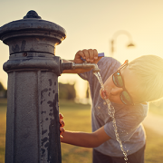 Little boy drinking water from public fountain