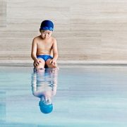 Little boy sitting by pool