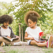 two kids reading books outside
