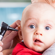 Pediatrician using otoscope on baby