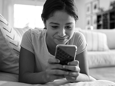 girl looking at smartphone on bed