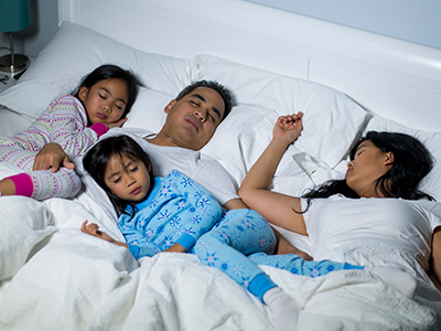 family sleeping in bed together
