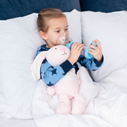 little girl in bed using an asthma inhaler