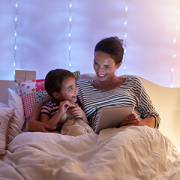 mom reading book to kid in bed
