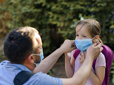father putting mask on daughter