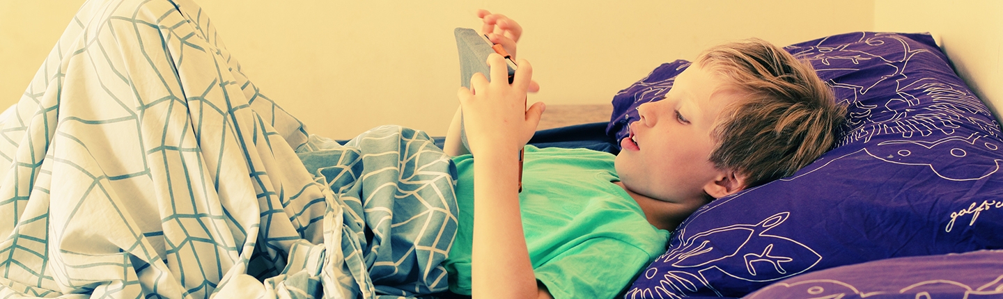 boy in bed using tablet