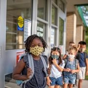 masked kids waiting in line for school